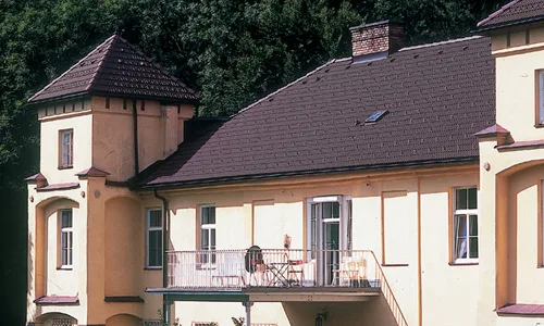 Pöglhof, Eckturm mit Balkon unter einem dunklen Walmdach