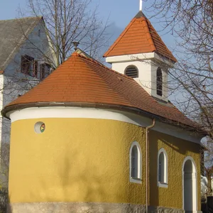 Kapelle mit rundem Turm, rotem Kegeldach und kleinem Glockentürmchen