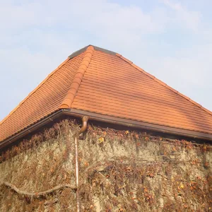 Rotes Ziegeldach aus der Nähe, Deckung über einer Natursteinmauer