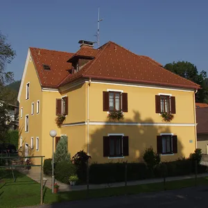 Wohnhaus mit rotem Ziegeldach, Fensterläden und zwei Kaminen